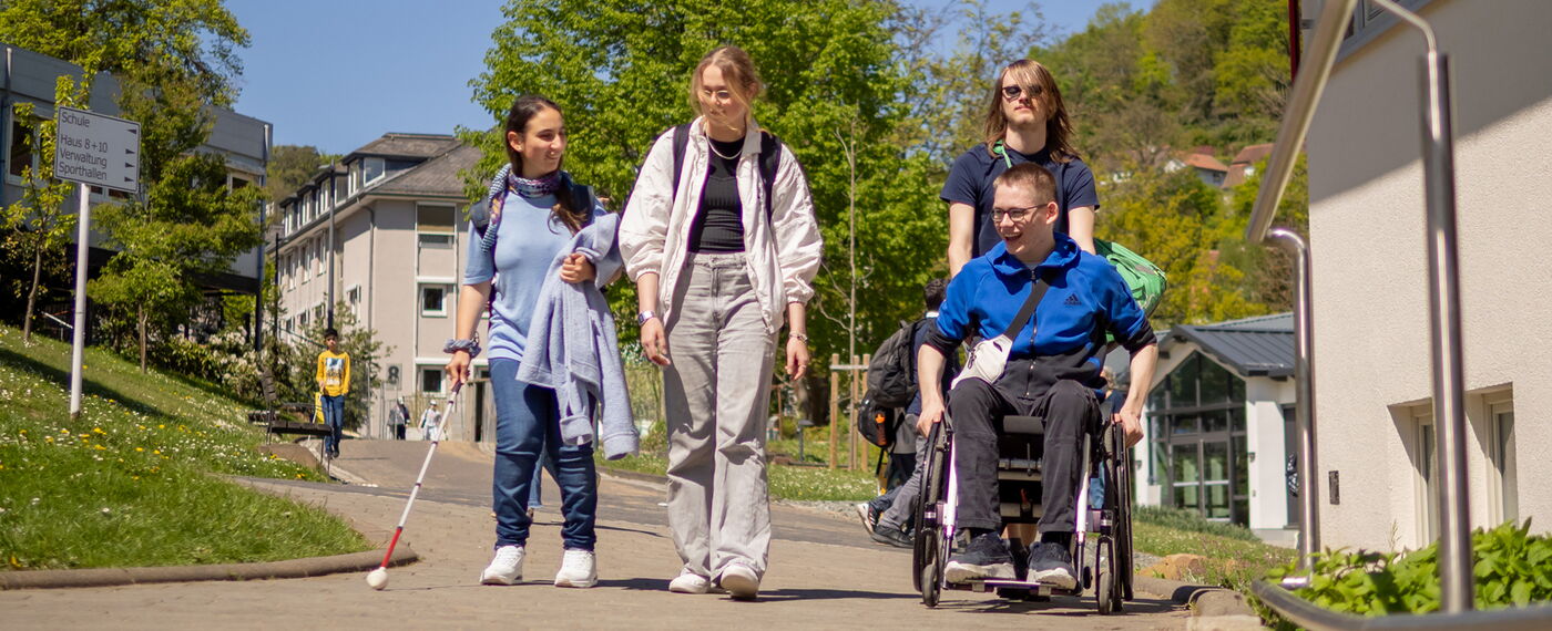 Eine Gruppe von vier Schüler*innen auf dem Campus.