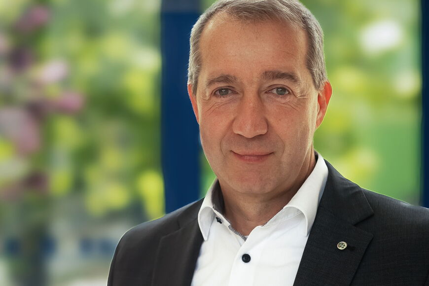 Portraitfoto Patrick Temmesfeld - er hat kurzes Haar und trägt ein schwarzes Sakko auf einem weißen Hemd mit dunklen Knöpfen.