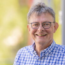 Portrait Bernd Wilhelm - er trägt eine Brille und ein kariertes Hemd.